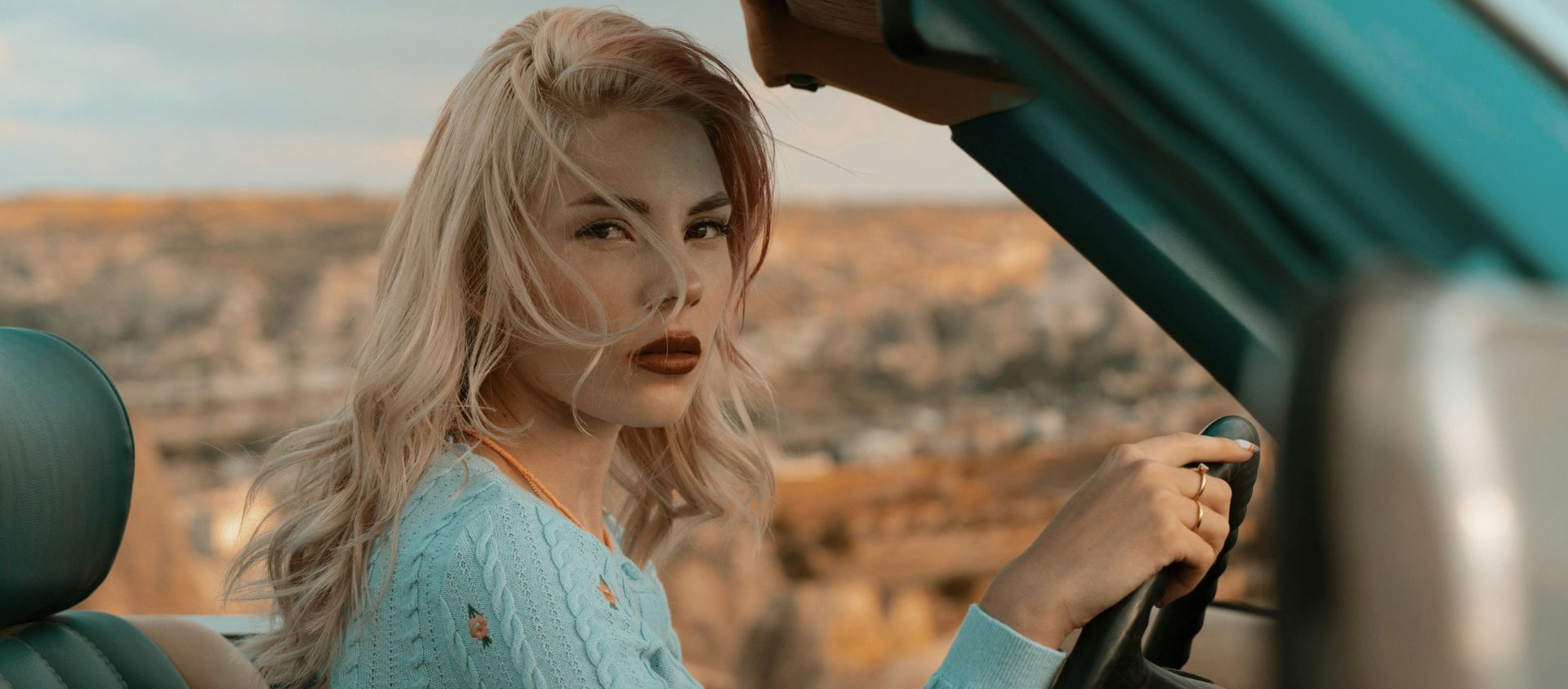 femme en bleu tenant le volant de la voiture pendant la journée